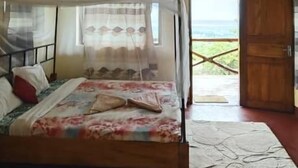 Quarto com cama, janela e porta de madeira.
