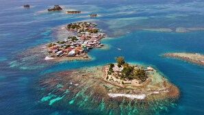 An aerial view of a coastal resort with multiple islands connected by bridges, featuring clear blue waters and a variety of buildings. - Lavender House at Treasure Beach - Secluded Beach House (Bay Islands Department)
