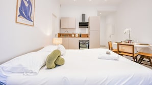 Ein Hotelzimmer mit Bett, einer kleinen Küchenzeile, einem Essbereich und einem gerahmten Kunstwerk an der Wand.