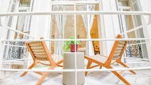 Ein Balkon mit zwei Holzstühlen, einem kleinen Tisch und einem Blumentopf.