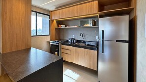 Eine moderne Küche mit Holzschränken, einem Edelstahlkühlschrank und einer schwarzen Arbeitsplatte.