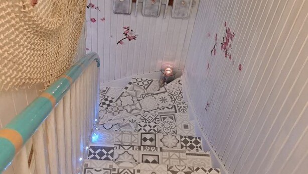 A narrow staircase with patterned tiles, a blue railing, and decorative wall elements.