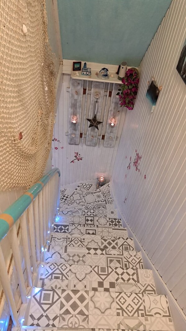 A narrow staircase with patterned tiles, a blue railing, and decorative wall elements.