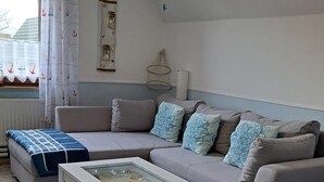 A living room with a grey sofa, a white coffee table, and a patterned throw blanket.