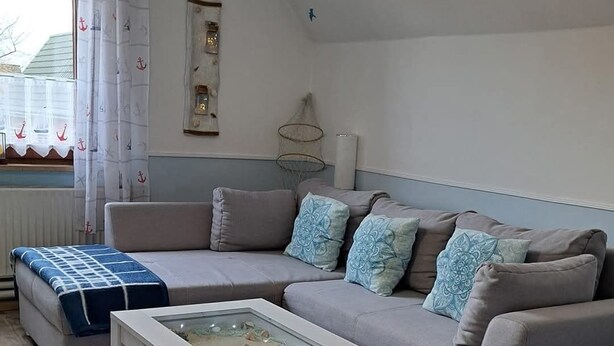 Un soggiorno con un divano grigio, un tavolino da caffè bianco e una coperta decorata.