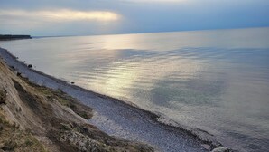 Un paisaje costero con una playa de piedras y un acantilado.