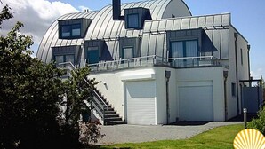 Una casa moderna con techo en forma de cúpula, una escalera que lleva a un balcón y un garaje.