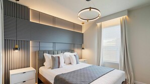 A modern bedroom with a large bed, bedside tables, a headboard, and a ceiling light fixture. - Stunning Pool Home just minutes from Disney 12 (Clermont)