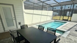 A covered patio with a pool, a table, and chairs. - Stunning Pool Home just minutes from Disney 12 (Clermont)