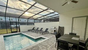 An outdoor pool area with a patio, lounge chairs, a grill, and a table. - Stunning Pool Home just minutes from Disney 12 (Clermont)