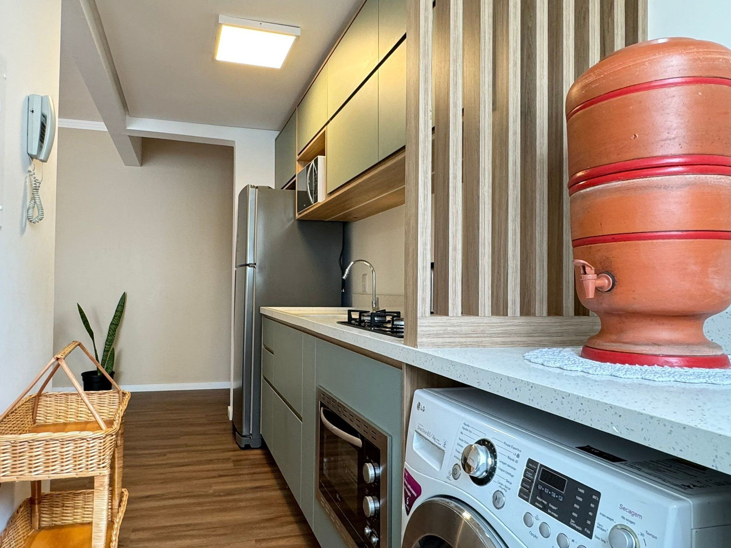 A compact kitchen with a built-in washing machine, a refrigerator, and a wooden cabinet.