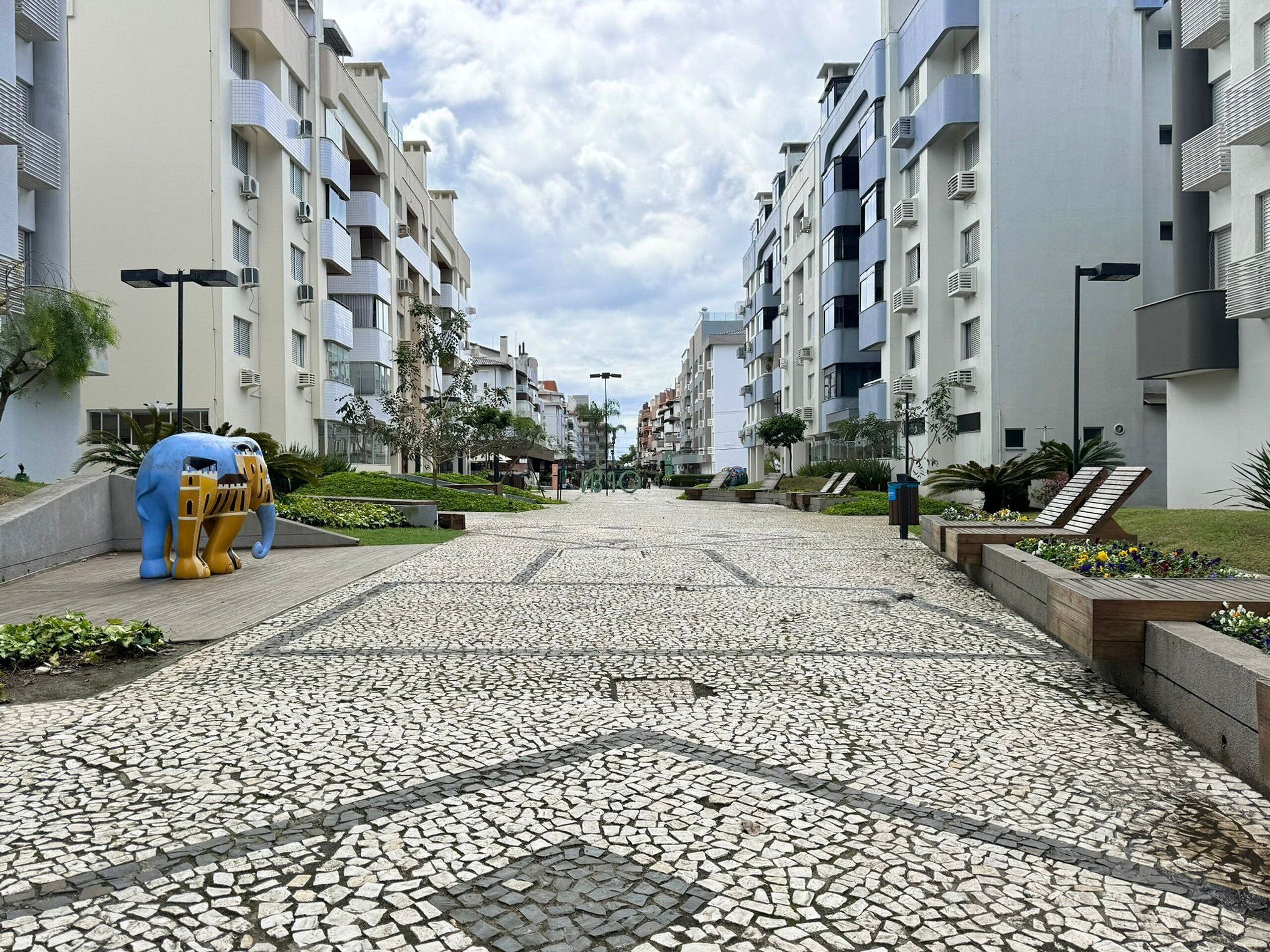 A modern residential building with a tiled walkway, a decorative elephant sculpture, and a well-maintained garden area.