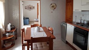 A compact kitchen with a dining table, chairs, a coffee machine, and a stove.