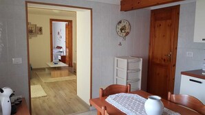 A compact kitchen with a wooden table, a white vase, and a clock on the wall.