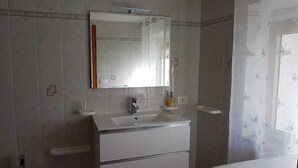 A bathroom with a white sink, mirror, and toilet.