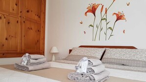A hotel room with a bed, a wooden wardrobe, and a wall with a floral mural.