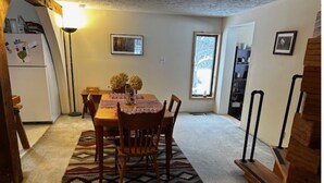 Un comedor con una mesa de madera, sillas y un tapete estampado.
