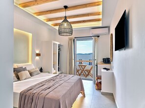Un dormitorio con cama, una lámpara colgante, televisor y vista al mar.