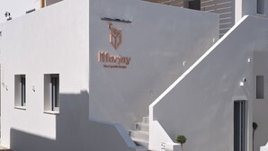 A modern building with a white facade, a logo with the name 'Marjay', and a wooden pergola. - Marjay (Paros)