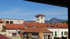 A town with red-tiled roofs, a bell tower, and a mountain in the background. - Burlamacco Gold modern rooms in the center of Viareggio 350 meters from the Sea (Viareggio)