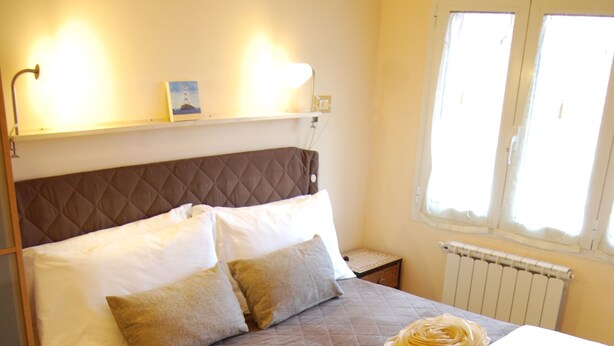 A neatly made bed with a brown quilt, white linens, and a rolled towel on the footboard. - Burlamacco Gold modern rooms in the center of Viareggio 350 meters from the Sea (Viareggio)
