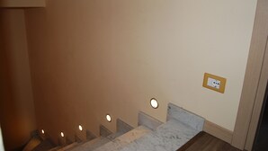 A staircase with a marble handrail and a wall-mounted light fixture. - Burlamacco Gold modern rooms in the center of Viareggio 350 meters from the Sea (Viareggio)