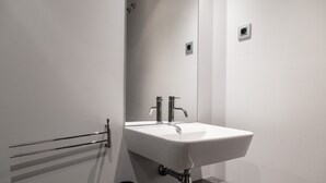 A bathroom with a white sink, chrome faucet, and a towel rack.