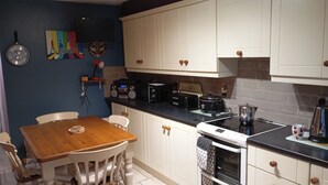 Una cocina con armarios blancos, una mesa de madera y un reloj en la pared.