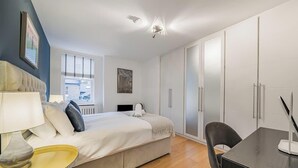 Une chambre à coucher avec un lit, une table de chevet, une lampe et une armoire.