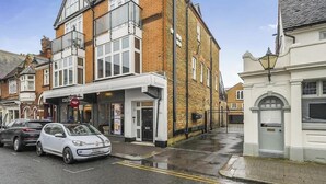 Une vue de rue avec une voiture blanche garée sur le bord, un bâtiment portant une enseigne indiquant « Costa » et un autre bâtiment avec une enseigne indiquant « Restaurant ».