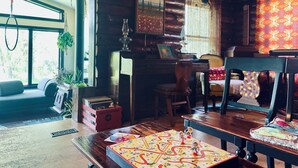 A cozy cabin interior with a wooden log wall, a large window, a dining table with a board game, a sofa, and a chair. - Your Tranquil Abode on the Holiday Road (Tipp City)