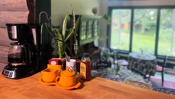 A coffee station with a coffee maker, yellow cups, and a jar of honey. - Your Tranquil Abode on the Holiday Road (Tipp City)