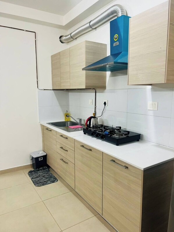 Una cocina moderna con armarios de madera, estufa a gas y campana extractora azul.
