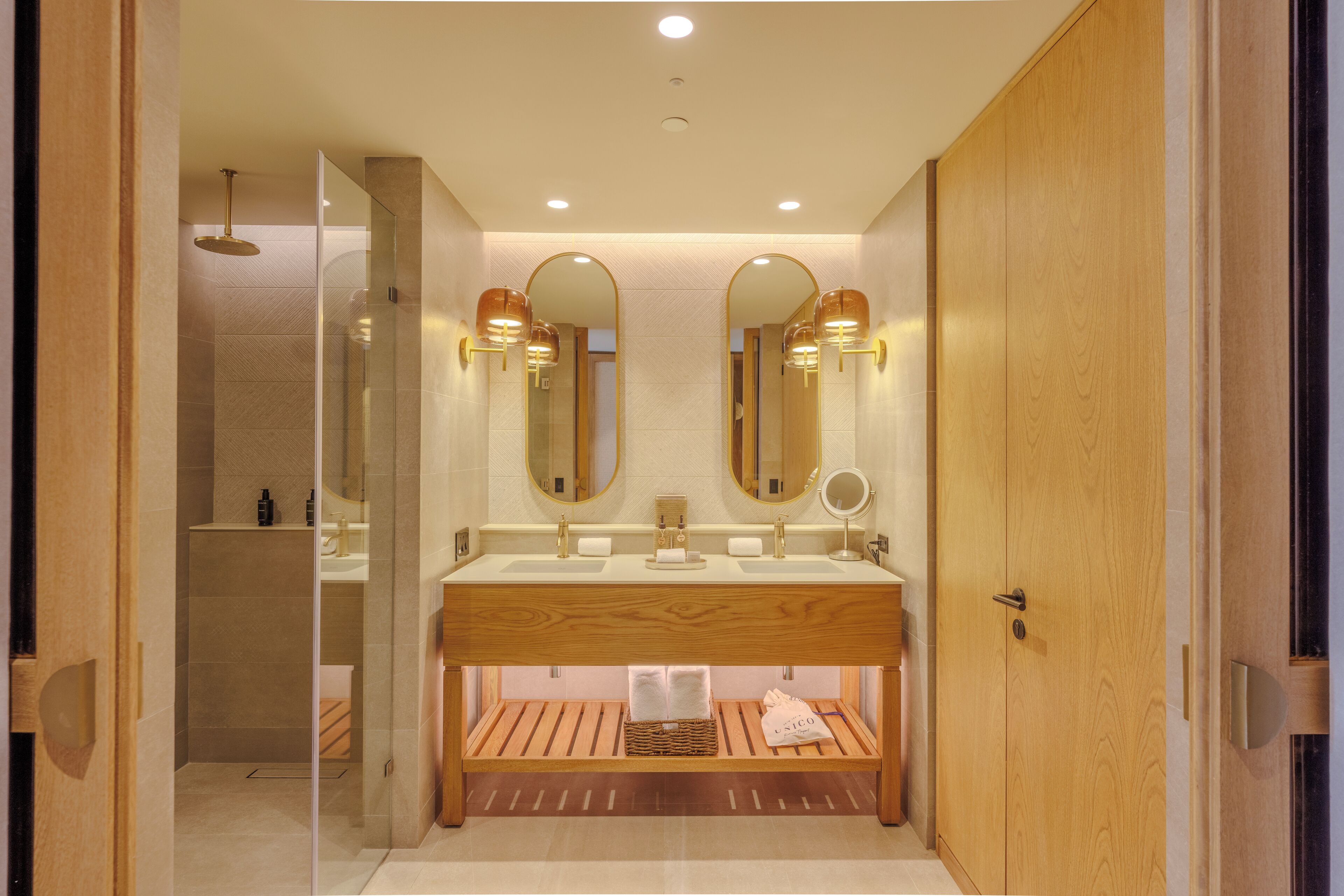 Un baño moderno con tocador de madera, dos espejos y ducha integrada.