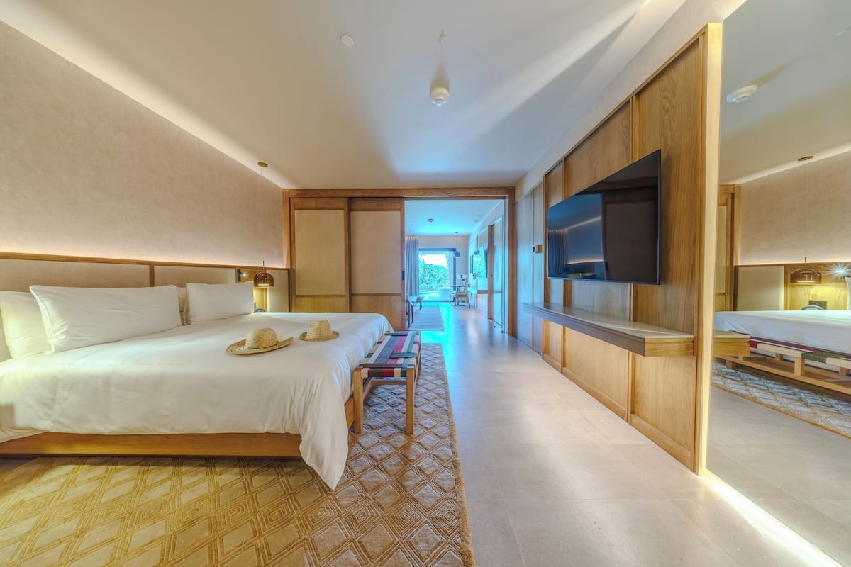 Ein modernes Hotelzimmer mit einem großen Bett, einem Flachbildfernseher und einem Holzschrank.