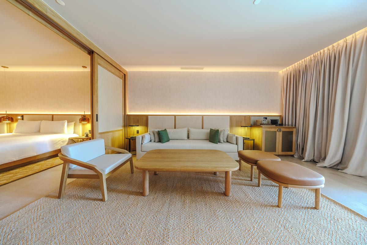 Ein Hotelzimmer mit einem Bett, einer Schlafcouch, einem Holztisch und einer Bank.