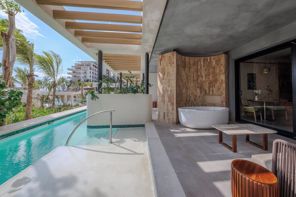 Ein moderner Poolbereich im Freien mit Whirlpool, Sitzgelegenheiten und Blick auf den Ozean.