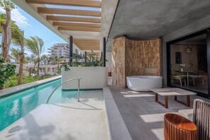 A modern outdoor pool area with a jacuzzi, seating, and a view of the ocean.