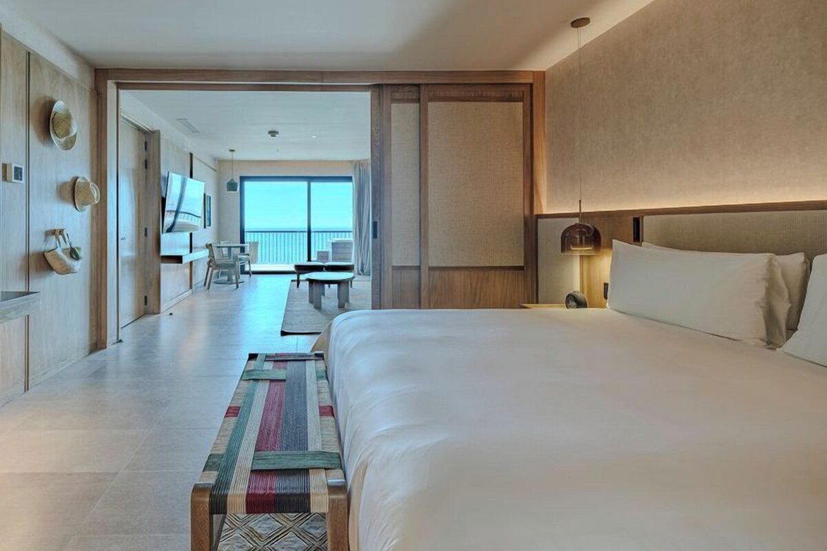 Une chambre d’hôtel avec un grand lit, un bureau et un balcon avec vue.