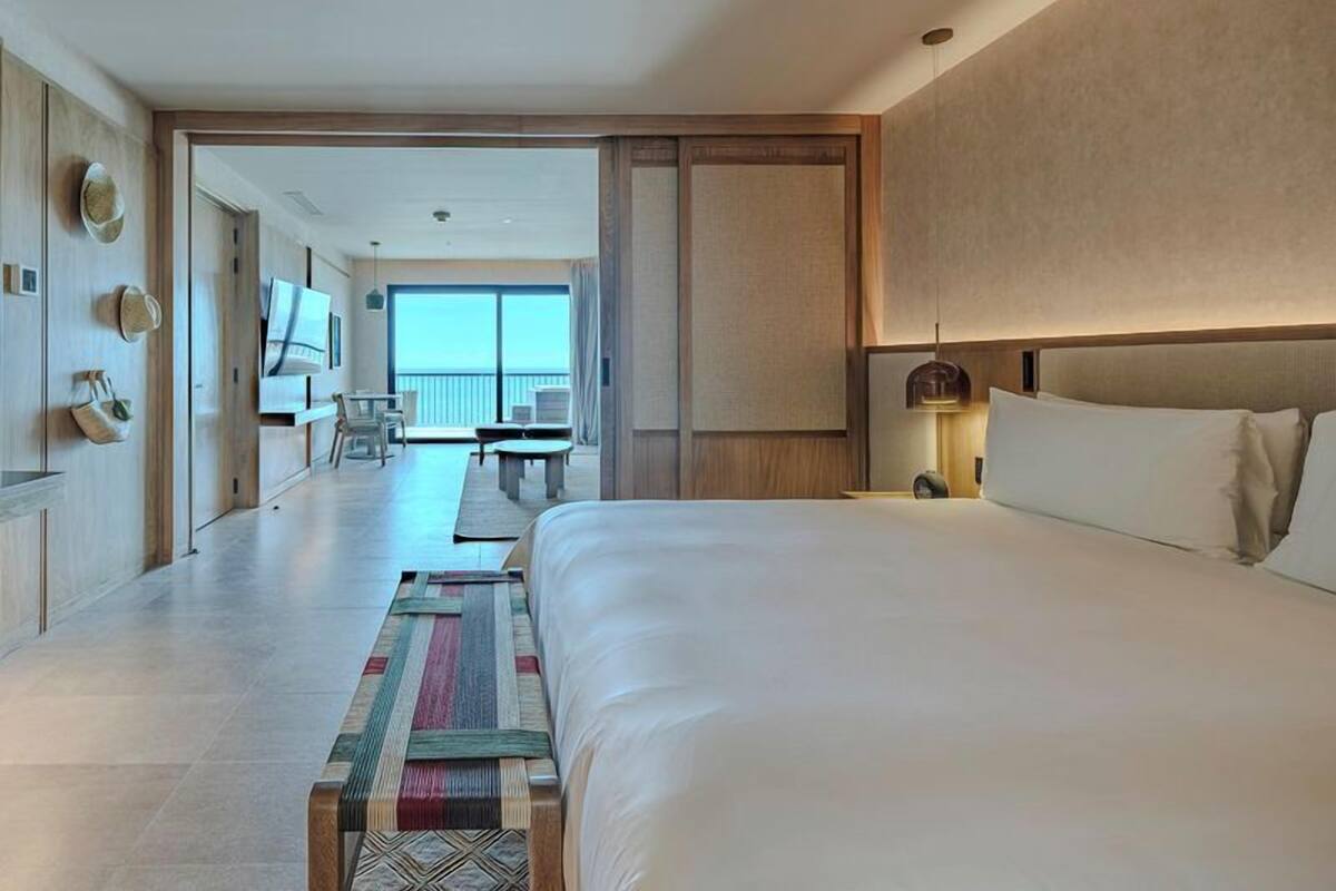 Ein Hotelzimmer mit einem großen Bett, einem Schreibtisch und Blick auf einen Balkon.