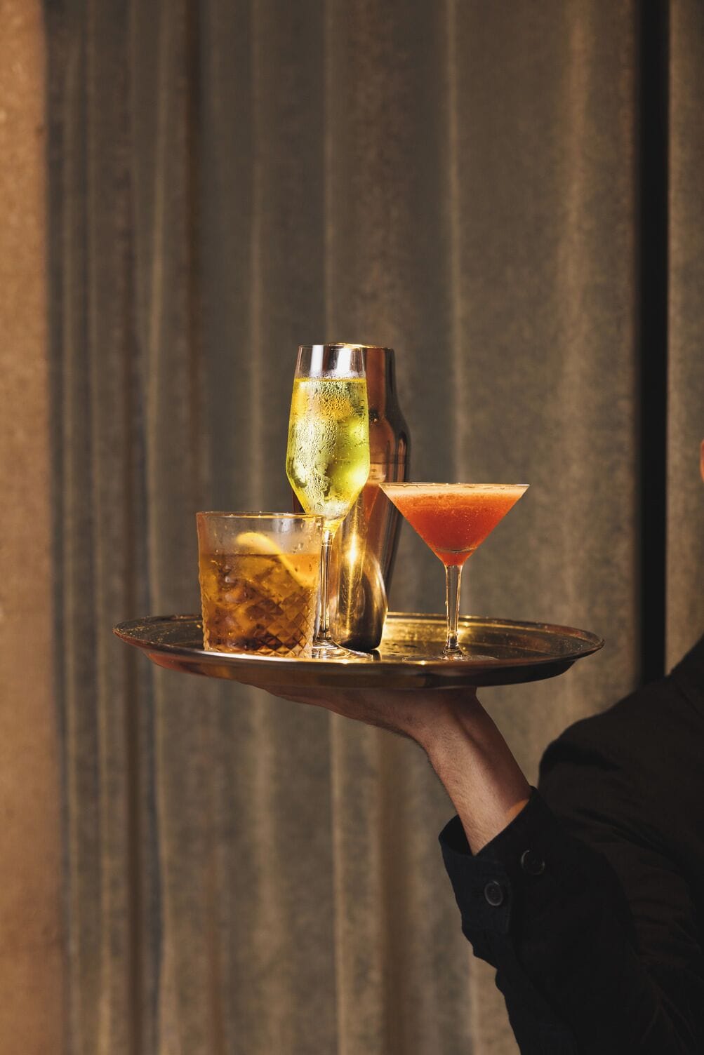 Een dienblad met drie drankjes, een karaf en een martini-glas.