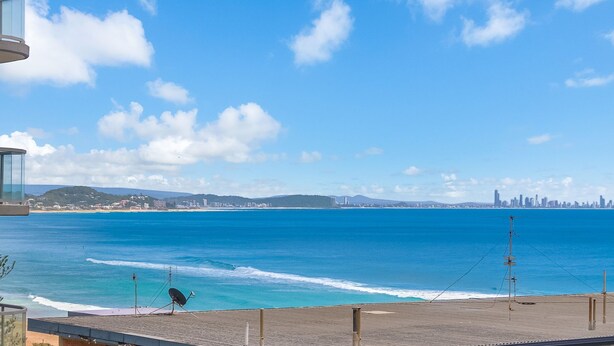 A coastal view with a beach, ocean, and distant city skyline.