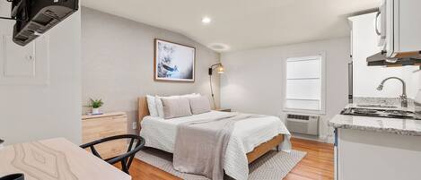 Una habitación pequeña y acogedora con cama, mesita de noche y un escritorio con silla.