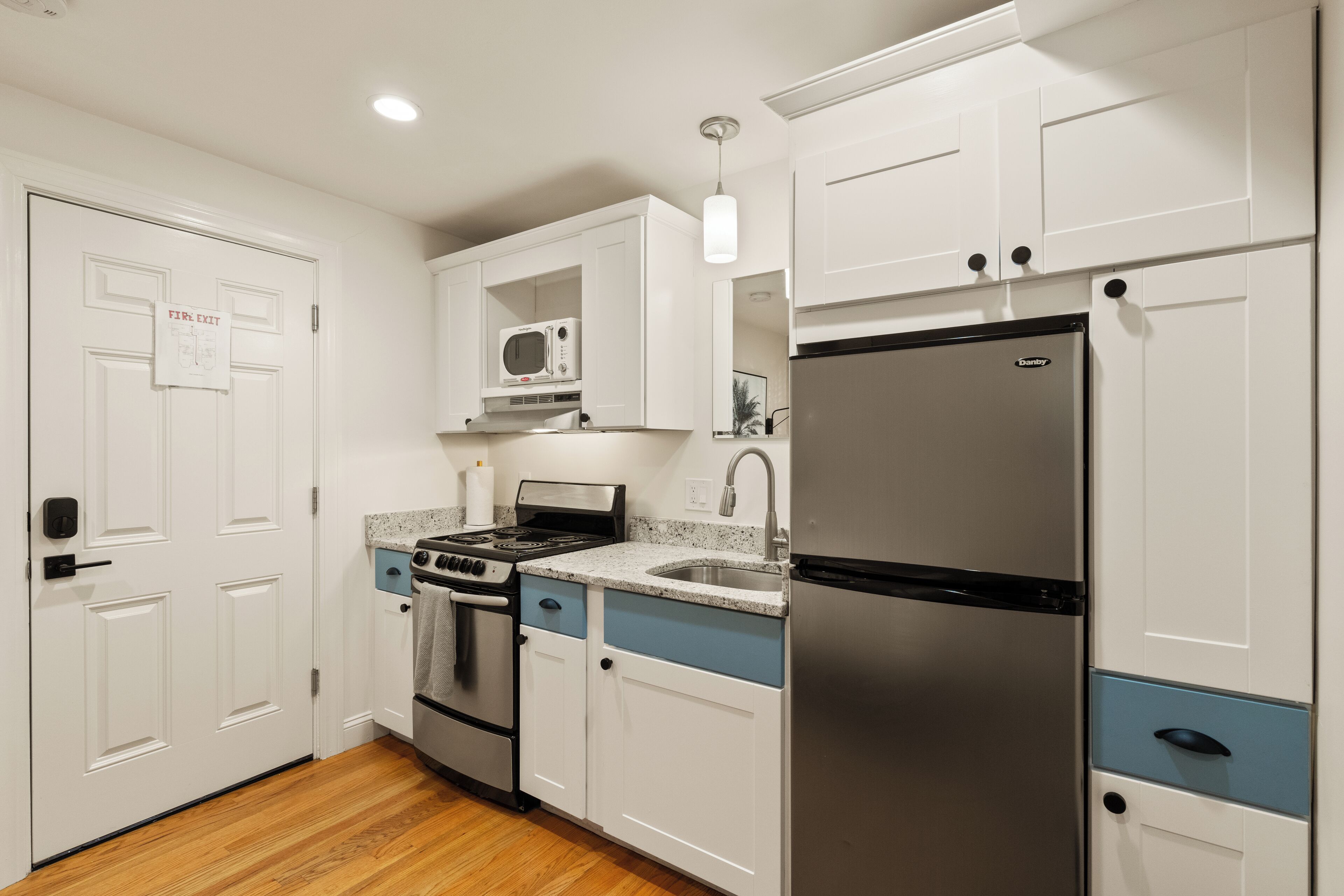 Una cocina moderna con armarios blancos, electrodomésticos de acero inoxidable y piso de madera.