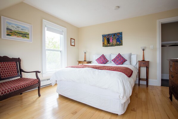 A bedroom with a large bed, a wooden bench, a nightstand, and a dresser.