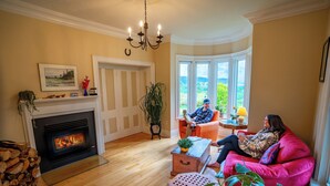 Un salon chaleureux avec une cheminée, une grande fenêtre offrant une belle vue et un coin salon confortable.