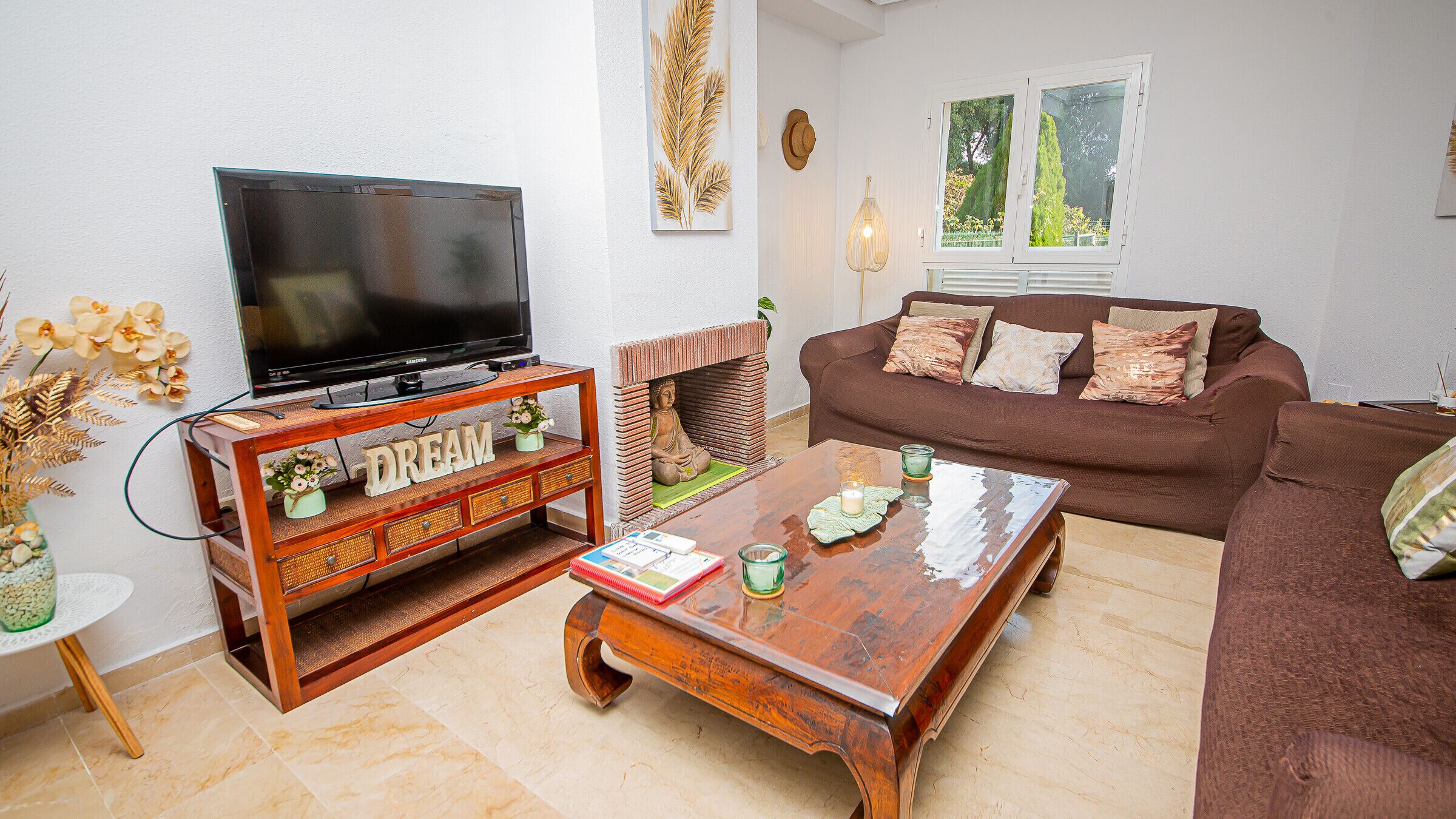 A living room with a television, a sofa, a coffee table, and decorative items.