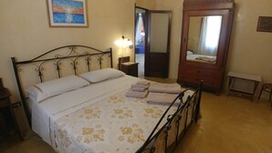 A neatly made bed with a floral bedspread, a bedside lamp, a wooden dresser, and a mirror. - Luxury villa in masseria- Rural hospitality (Sannicola)