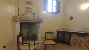 A room with a fireplace, two wooden chairs, a table with a laptop, and a window with shutters. - Luxury villa in masseria- Rural hospitality (Sannicola)