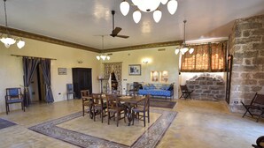 A spacious living room with a dining area, a stone fireplace, and a ceiling fan. - Luxury villa in masseria- Rural hospitality (Sannicola)